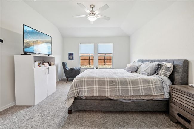 Bedroom featuring light colored carpet, vaulted ceiling, and a ceiling fan | Image 11
