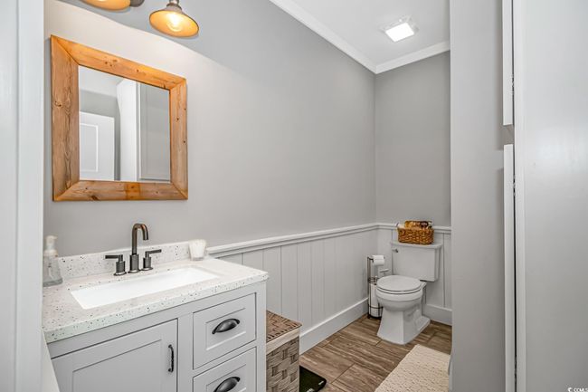 Bathroom with vanity, crown molding, wood finished floors, and a wainscoted wall | Image 15