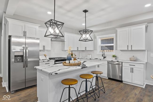 kitchen with quartz counter-tops, soft close cabinets, decorative backsplash, chandeliers, recessed lighting, stainless steel appliances, huge island and a farmers sink | Image 8