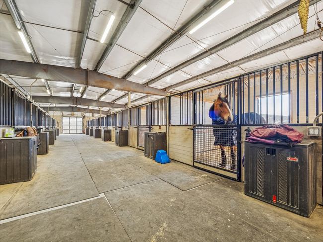 Stables featuring oversized stalls with stall mattresses, 2 hot and cold water wash bays, wide, well lit aisleway, modern efficiency lighting, heat, underground utilities and Nelson automatic waterers in stalls | Image 6