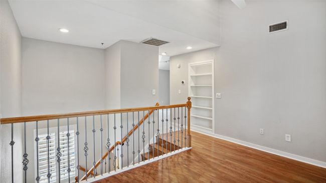 Corridor featuring wood finished floors, an upstairs landing, baseboards, built in shelves, and recessed lighting | Image 16