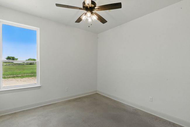 Unfurnished room with concrete floors, baseboards, and ceiling fan | Image 20