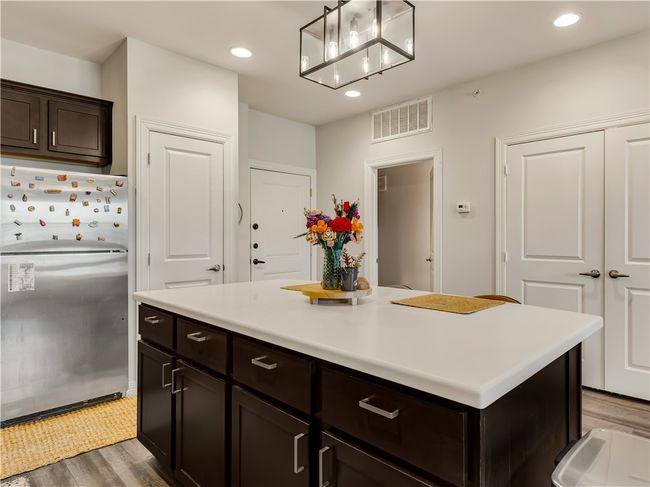 Kitchen featuring hardwood / wood-style flooring, hanging light fixtures, stainless steel built in refrigerator, dark brown cabinetry, and a kitchen island | Image 14