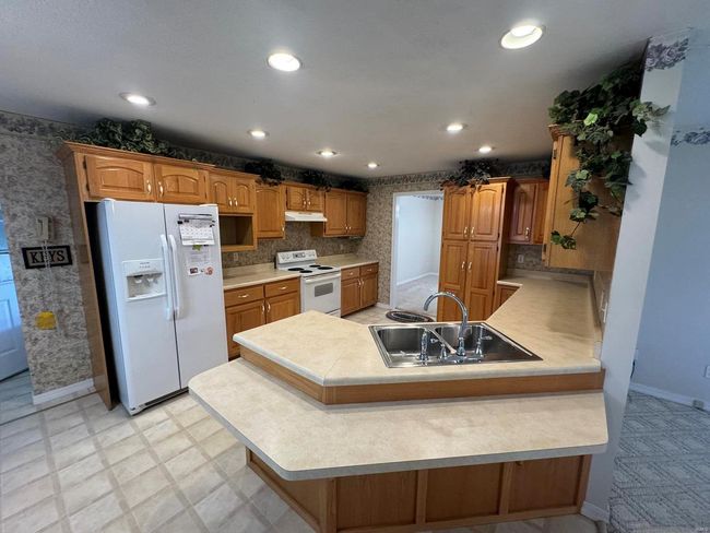 Kitchen featuring white appliances, a kitchen bar, sink, and kitchen peninsula | Image 4