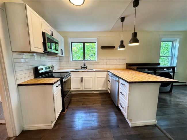 Kitchen featuring a healthy amount of sunlight, white cabinetry, kitchen peninsula, wood counters, and appliances with stainless steel finishes | Image 4