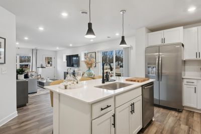 (*Photo of decorated model, actual homes colors and finishes will vary) The kitchen is home to a large center island complete with quartz countertops, stainless appliances, and a luxurious gas cooktop. | Image 3