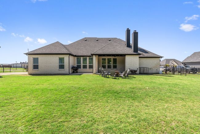 Rear view of property featuring a fenced backyard, roof with shingles, and a chimney | Image 31