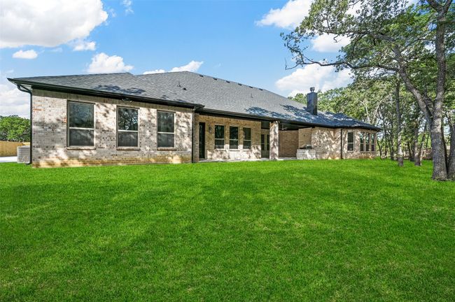 Rear view of property with a shingled roof, brick siding, a lawn, and a chimney | Image 12