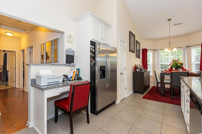 Kitchen with hanging light fixtures, stainless steel fridge with ice dispenser, visible vents, white cabinets, and dishwashing machine | Image 11