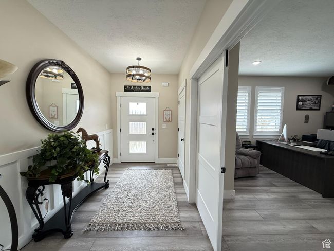 Foyer featuring wood finished floors, a notable chandelier, baseboards, and a textured ceiling | Image 7
