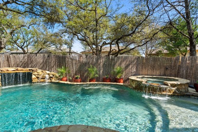 View of swimming pool with a fenced backyard and a pool with connected hot tub | Image 35