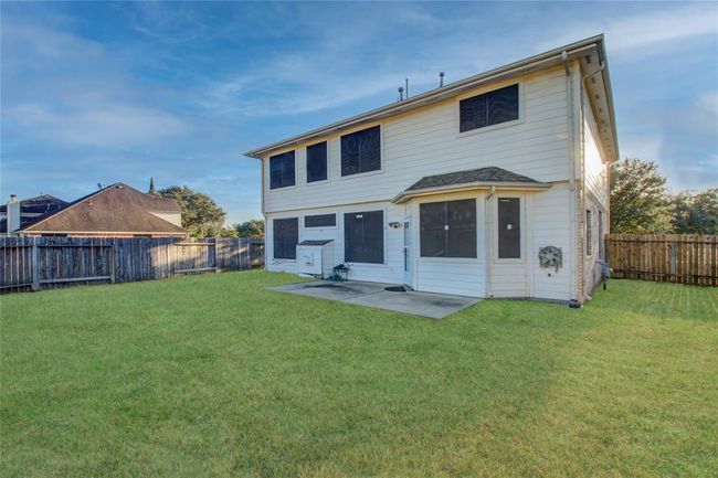 Spacious two-story home with a large fenced backyard, perfect for outdoor activities. Features multiple windows for natural light and a patio area ideal for relaxation or entertaining. | Image 4