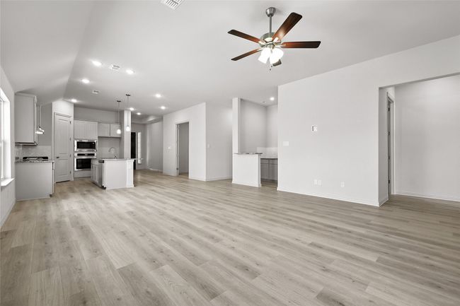 Unfurnished living room featuring ceiling fan, light wood-type flooring, recessed lighting, and vaulted ceiling | Image 16