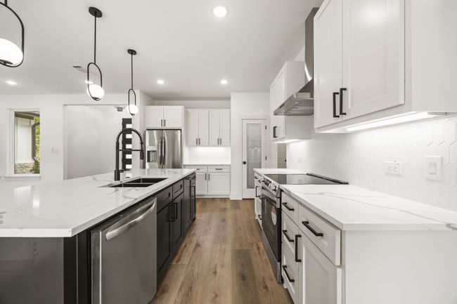 Kitchen with stainless steel appliances, a sink, tasteful backsplash, wall chimney exhaust hood, and light wood-type flooring | Image 9