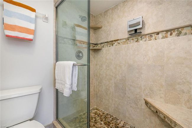 OWNER'S SUITE SHOWER. FULL-HEIGHT TILED WALLS WITH DECORATIVE BORDER. BUILT-IN SHELVES AND SEAT. GLASS SLIDING DOORS. | Image 18
