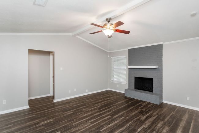 Unfurnished living room featuring ceiling fan, dark wood finished floors, and a fireplace | Image 6