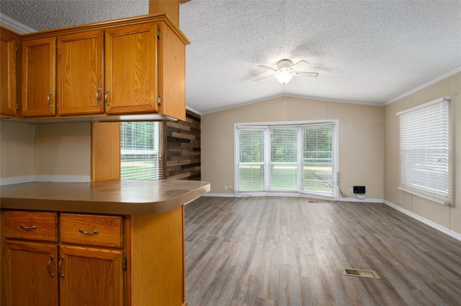 Kitchen with ceiling fan, brown cabinetry, wood finished floors, vaulted ceiling, and baseboards | Image 26