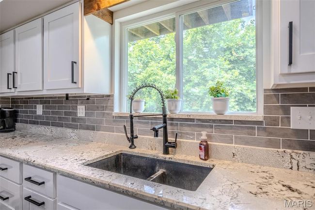 Kitchen with white cabinetry, tasteful backsplash, light stone countertops, and plenty of natural light | Image 24
