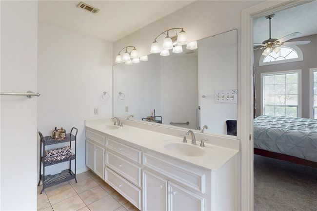 Ensuite bathroom with double vanity, tile patterned floors, and ceiling fan | Image 22