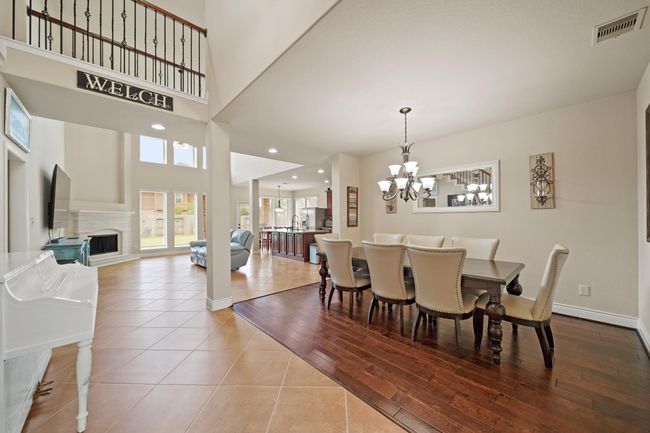 This spacious open-concept home features a bright living area with high ceilings, a cozy fireplace, and large windows. The dining area offers elegant wood flooring and a stylish chandelier. The space seamlessly connects to the kitchen, perfect for entertaining. | Image 9