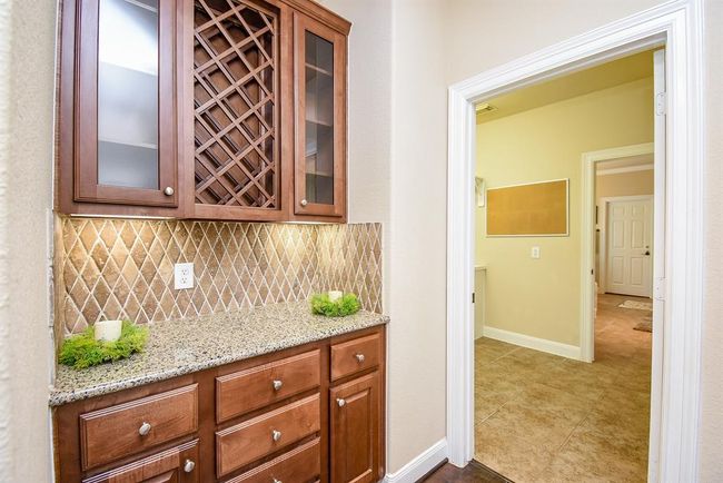 This butler’s pantry features a built-in wine rack, granite countertop, and glass-front cabinetry that beautifully displays your favorite pieces while streamlining service. | Image 7