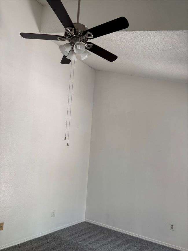 Unfurnished room featuring baseboards, dark carpet, a textured ceiling, and ceiling fan | Image 14