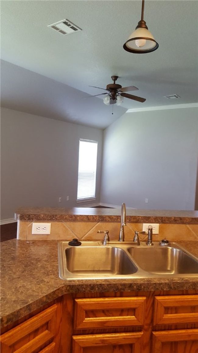 Kitchen featuring a ceiling fan, dark countertops, and brown cabinetry | Image 6