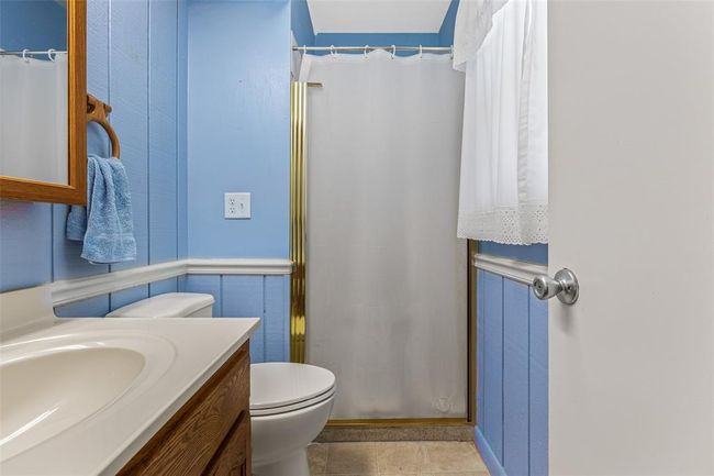 Bathroom with vanity, toilet, a shower with curtain, and tile patterned floors | Image 58