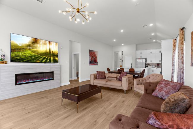 Living area featuring light wood-type flooring, recessed lighting, a chandelier, vaulted ceiling, and baseboards | Image 15