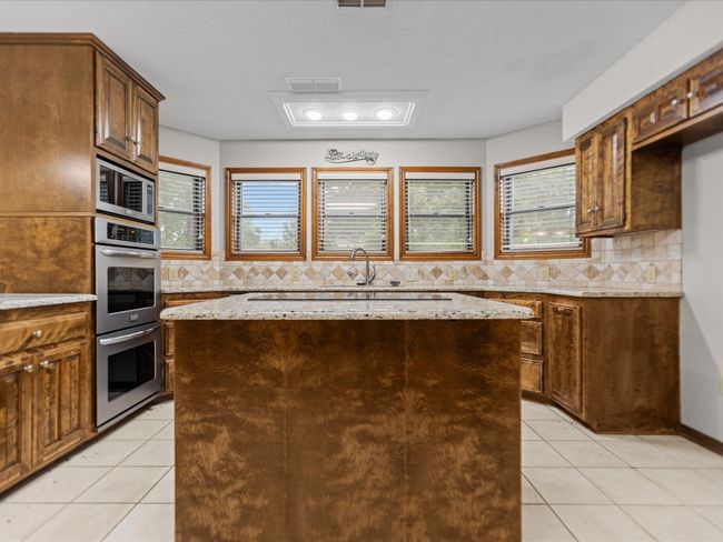 Kitchen with appliances with stainless steel finishes, a center island, light tile patterned floors, and tasteful backsplash | Image 16