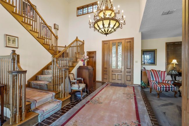 Tiled entrance foyer featuring a textured ceiling, a high ceiling, and a notable chandelier | Image 8