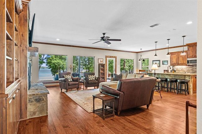 Living room with a wealth of natural light, ornamental molding, light hardwood / wood-style flooring, and ceiling fan | Image 6