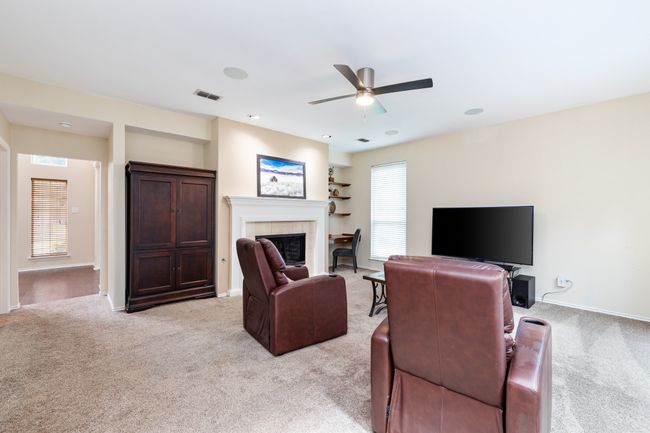 Living area featuring ceiling fan, a fireplace, light colored carpet, and recessed lighting | Image 12