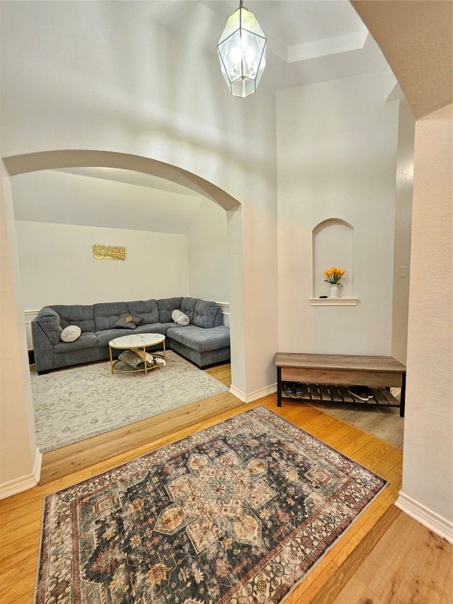 Living room with arched walkways, wood finished floors, and a chandelier | Image 15