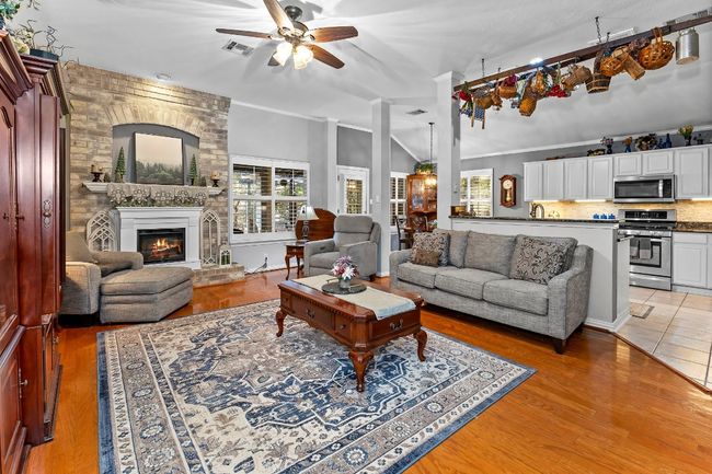 Living room featuring crown molding, ceiling fan, a brick fireplace, and light hardwood / wood-style flooring | Image 6