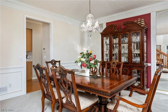 Dining room featuring light carpet, an inviting chandelier, and ornamental molding | Image 15