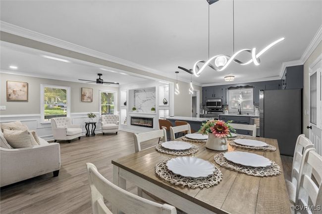 Dining room with ornamental molding, wood finished floors, a glass covered fireplace, a decorative wall, and ceiling fan | Image 20