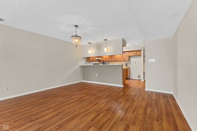 unfurnished living room with dark wood-style flooring, a chandelier, baseboards, and a textured ceiling | Image 12