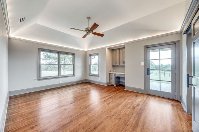 Unfurnished living room featuring built in study area, plenty of natural light, light wood-type flooring, and ceiling fan | Image 13