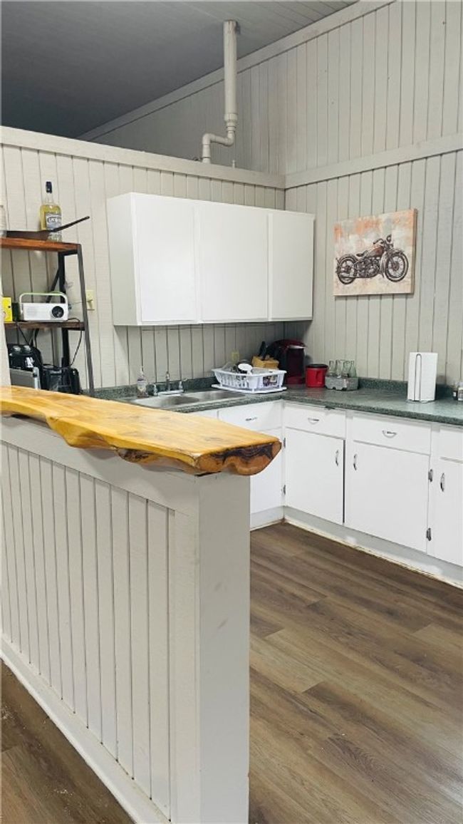 Kitchen with white cabinetry, dark hardwood / wood-style floors, and wood walls | Image 4