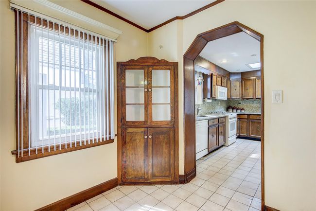 Kitchen featuring white appliances, tasteful backsplash, light tile patterned flooring, and ornamental molding | Image 9