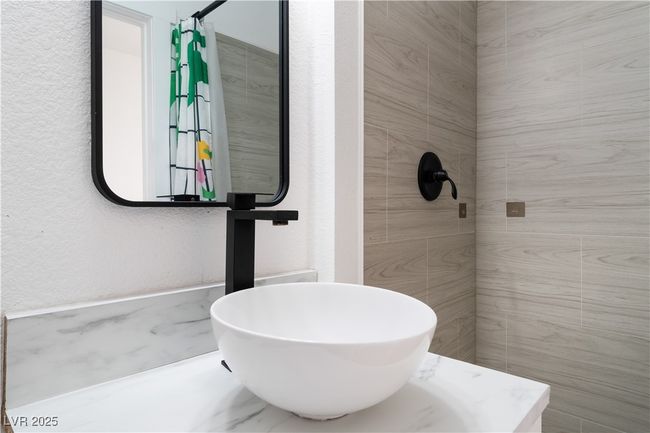 Full bath featuring a tile shower, a textured wall, and a sink | Image 30