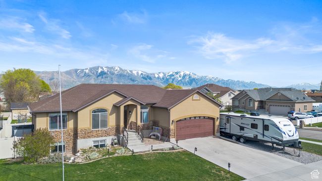 View of front of property featuring driveway, stone siding, a mountain view, stucco siding, and a garage | Image 44