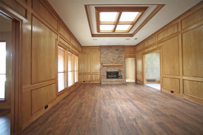 Unfurnished living room with a decorative wall, a brick fireplace, and dark wood finished floors | Image 9