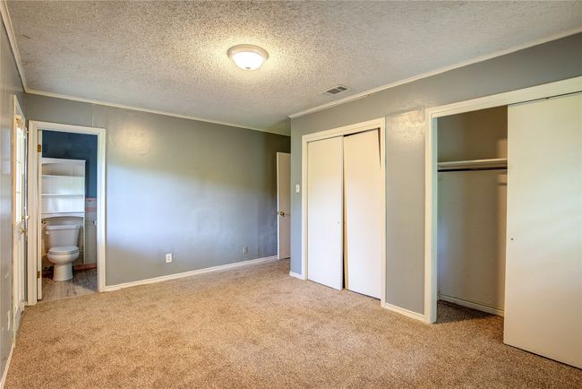 Unfurnished bedroom featuring two closets, carpet, ornamental molding, a textured ceiling, and ensuite bath | Image 23