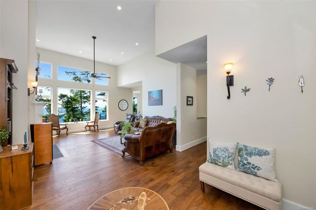 Living room with a high ceiling, wood finished floors, recessed lighting, and a ceiling fan | Image 41