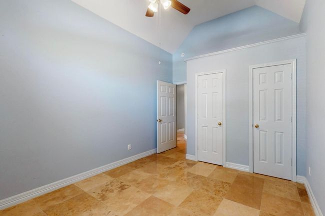 Unfurnished bedroom with baseboards, a ceiling fan, and vaulted ceiling | Image 28