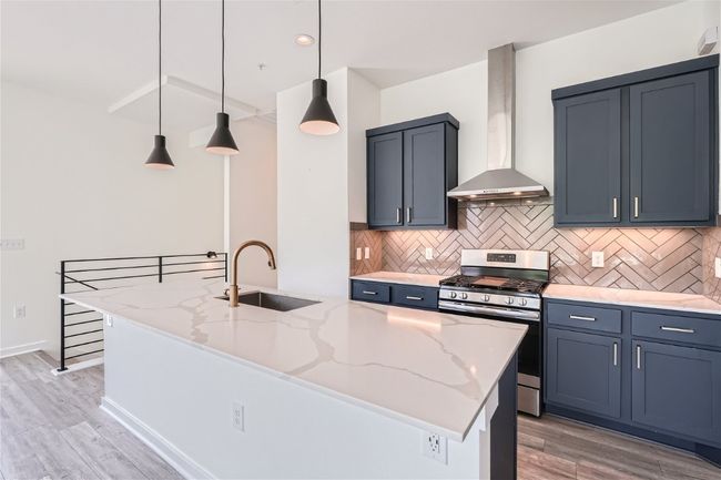 The beautiful kitchen features a spacious quartz island, perfect for barstools, complemented by elegant navy blue cabinets. | Image 20
