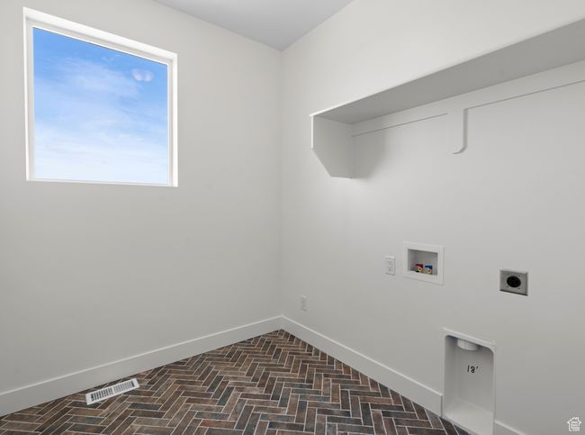 Clothes washing area with baseboards, brick floor, laundry area, and hookup for an electric dryer | Image 10