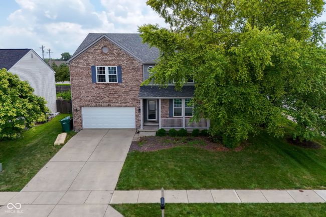 traditional-style house with brick siding, concrete driveway, an attached garage, a front yard, and roof with shingles | Image 45